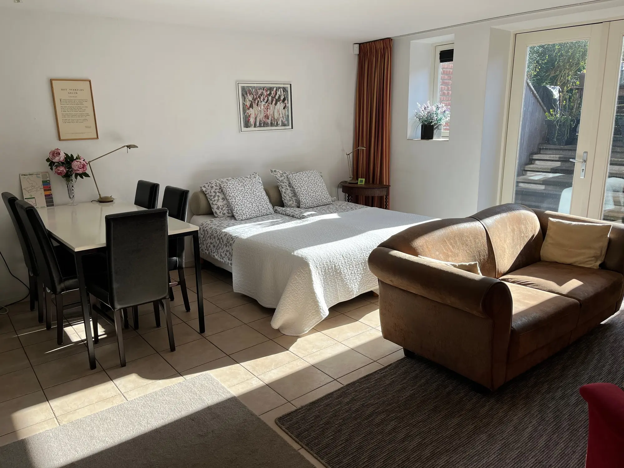 De lichte studio met bedden, fauteuil en tafel